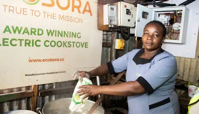 Photo of Prof. Purity, with an Ecobara solar cooking boiler at the Prosperity Self Help Group